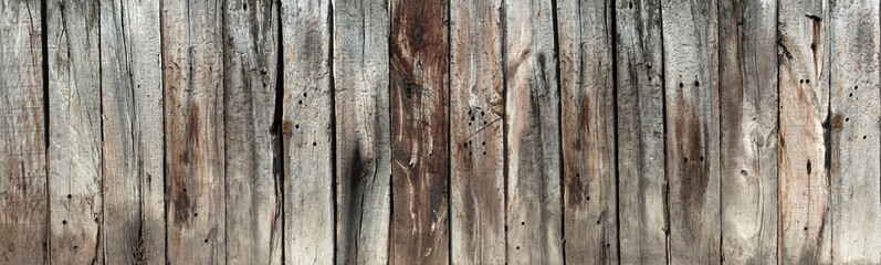 Vertikale Reihe aus alten, vertikalen, verwitterten, grau braunen Holzbohlen - Panorama Detail