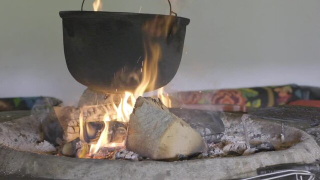 100 fps slow motion video of cooking food in traditional cauldron fire.