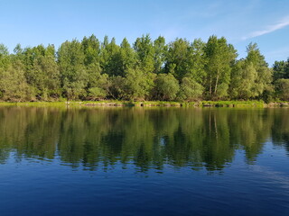 Fototapeta na wymiar Beautiful scenery of a range of green trees reflecting in the lake