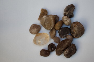 pebbles of different sizes and textures spread out on a rustic white background.
