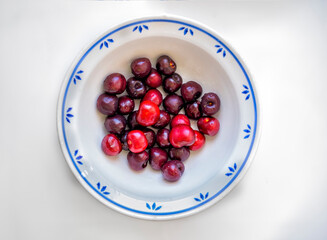 decorated plate full of large cherries over white backround