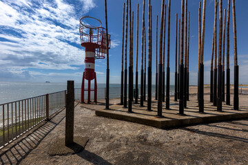 Vlissingen - white-red lighthouse by the wind organ on Badstrand beach. In the background the blue...