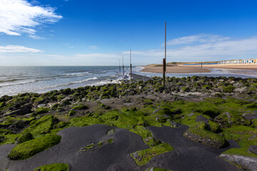 Fototapeta premium Vlissingen - beautiful sandy beach with colorful houses in a row. In the middle of the path of wooden planks. Sunny, quiet, relaxing place in the bay.