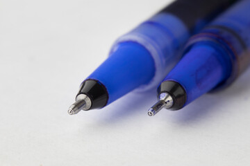 macro photo of the blue ballpoint pen on the white page paper