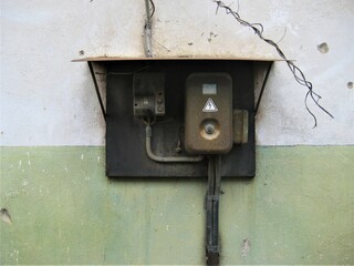 an old rusty electrical panel on a scuffed building wall