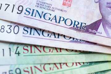 Obverse of Singapore Two 2 dollar SGD polymer banknotes overlapping with bills of different denominations. Close-up.