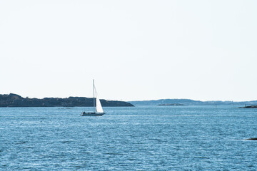 Lonely sailboat crossing a calm bay.