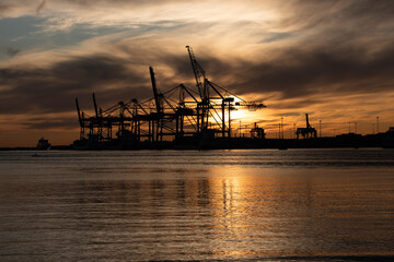 Fototapeta na wymiar Silhouettes of ship to shore cranes at sunset.