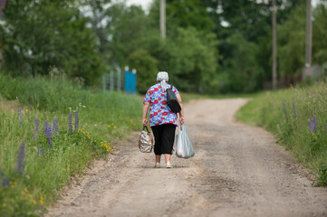 
old woman drags heavy bags along the road