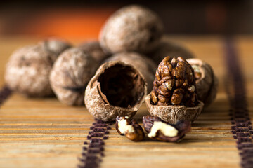 Walnut kernels on dark table with color background, whole walnuts in wooden vintage bowl.