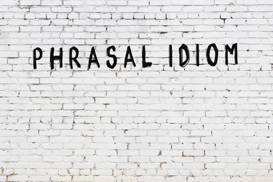 Word phrasal idiom painted on white brick wall