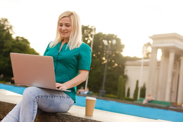 woman searching job with a laptop in an urban park in summer