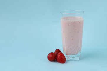 Fresh natural homemade berry strawberry yogurt in a glass Cup and strawberries next to it on a blue background. Selective focus. Space for text. Healthy vitamin snack