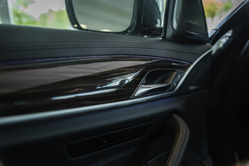 open door handle of a modern car with wooden/ leather interior