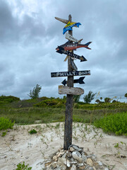 A city directional sign at a beach showing how far cities are from this point on a beach