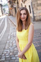 Fototapeta premium Pretty long hair brunette girl in yellow light dress walking outdoor