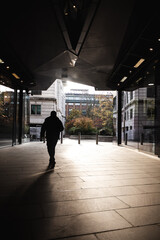 Silhouette of a man waking in a shopping centre on a bright sunny day