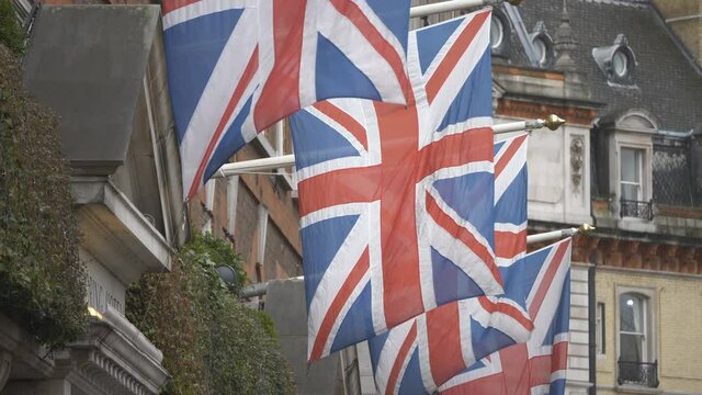 A row of British flags on the rooftops of buildings.