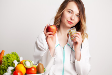 Nutritionist holding omega-3 fish oil vitamin tablet and fresh fruit in her room recording a video blog on her phone