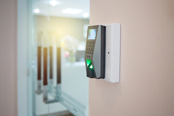 Fingerprints scanner machine to access interior on the wall in front of blur office background. Selective Focus.