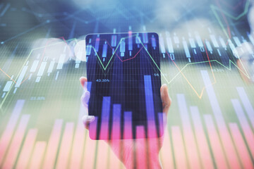 Double exposure of forex chart sketch hologram and woman holding and using a mobile device. Financial market concept.