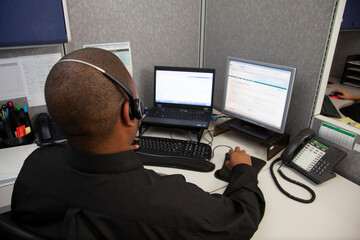 young man with computer and headset shot from behind
