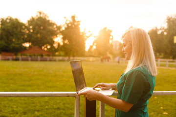 beautiful young blond woman with a laptop in the park on a warm summer day