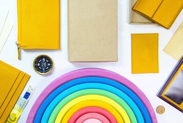 Travell and shopping concept with yellow wallets, 20 euro banknote, compass, coin, children toy rainbow and accessories, overhead flatlay stop motion. Top view