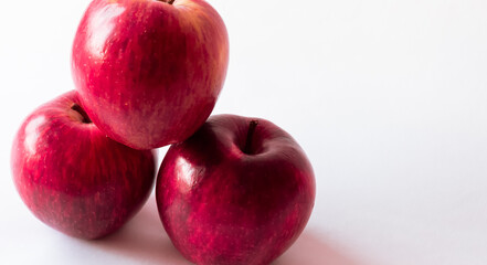 Plano levemente en contra picado de tres frescas y rojas manzanas completamente aisladas sobre un fondo blanco total con iluminación natural