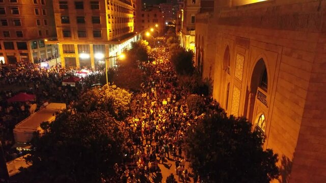 Beirut, Lebanon 2019 : night drone shot ped up from road leading to Riyadh El Soleh square then revealing church and mosque while thousands of protesters are revolting during the Lebanese revolution
