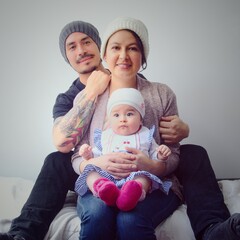 Padres jóvenes con su pequeño bebé vistiendo gorros. Retrato de padres jóvenes y su pequeña hija. Familia de padres jóvenes. 