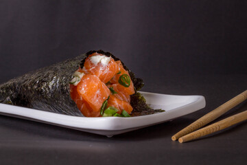 Salmon temaki sushi on white plate in black background