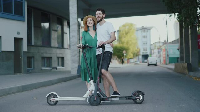 Portrait of happy couple in love stands in embraces with electric scooters