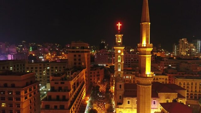 Beirut, Lebanon 2019 : night drone shot ped down from church and mosque then revealing road leading to Riyadh El Soleh square while thousands of protesters are revolting during the Lebanese revolution