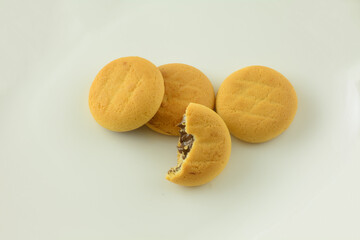 Soft baked cookies with chocolate filling and one with missing bite in white background