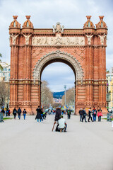 Young male photographer taking pictures using a vintage wooden camera at the Triumphal Arch in Barcelona
