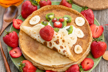 Pancakes with kiwi, bananas and strawberries for Breakfast. An edible bear of fruit and berries covered with a pancake.