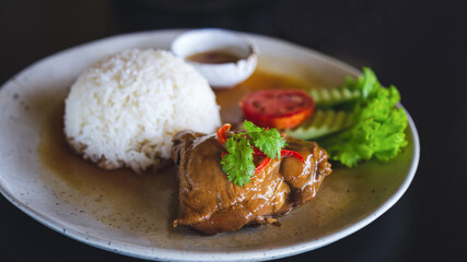 Rice with Roast Chicken in a white plate on a black table.
