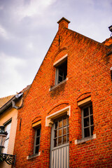 Naklejka premium It's Medieval houses with flowers at the windows in the Historic Centre of Bruges, Belgium. part of the UNESCO World Heritage site