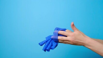 Close up of unrecognizable young woman removes medical gloves and throw it in trash, isolated on blue studio background with copy space for advertisement. Concept end of virus epidemic  - Powered by Adobe