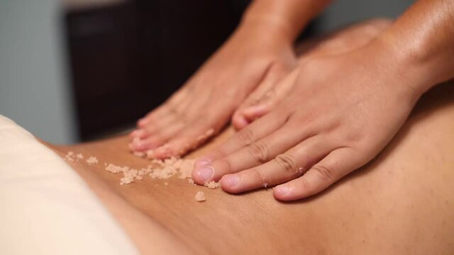 Slow motion video of a masseur giving a body scrub treatment
