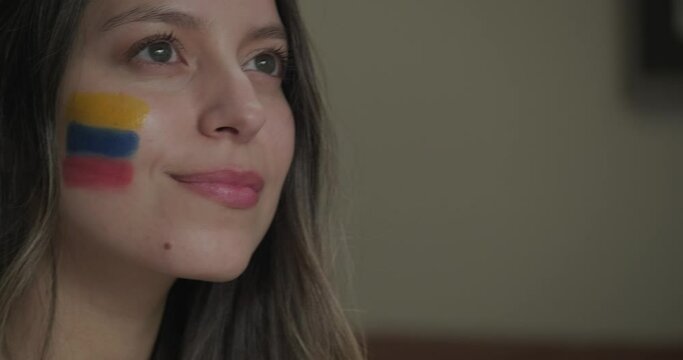 Female Colombian football supporter with the flag on her cheek looking up