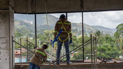 Construction workers repair window to a building. Workers in full person protective equipment, to...