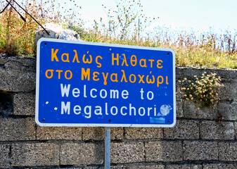 A welcome sign to the village of Megalochori in Santorini in Greece. The sign is also written in the Greek language.