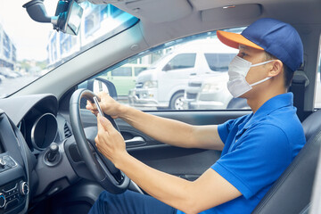 Asian delivery man courier online using mobile phone contact the customer. He wears a mask to...