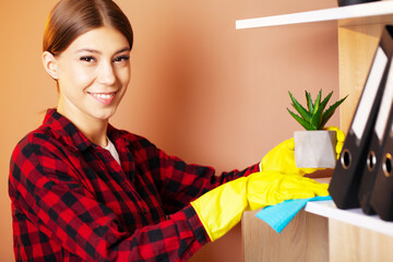 An employee of a cleaning company wipes the dust on the plants.