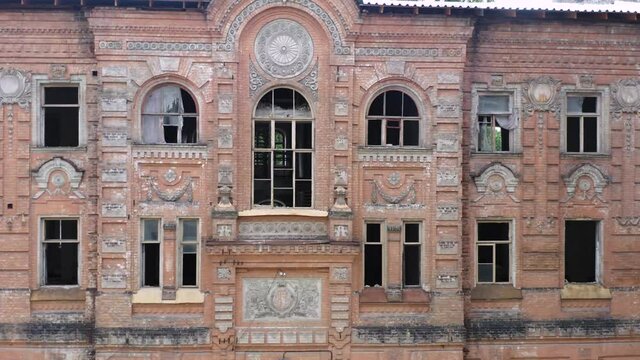 Abandoned palace or manor (mansion) house in the neoclassical style with an abundance of decor and broken windows. Deserted old buildings of the 19th century. Aerial side view.