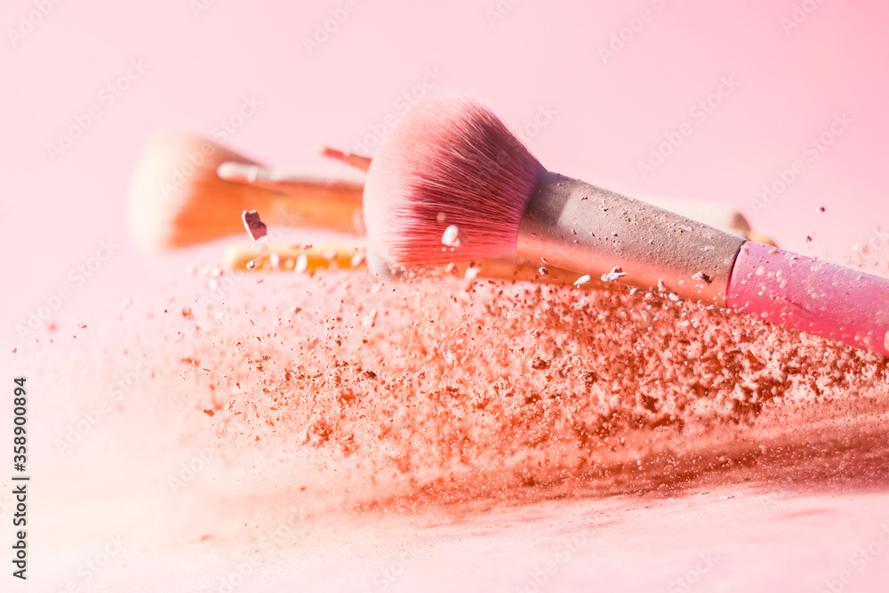 Wall mural Make up brushes with powder splashes isolated on pink background