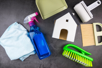 Wooden model white houses and house cleaning equipment on cement gray background. Concept Clean house Keep house clean.