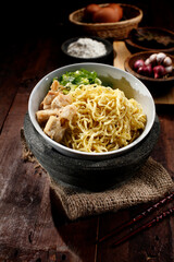 Chicken noodle. A bowl of boiled noodles is given a spice of broth and a sprinkling of pieces of chicken and leeks and celery. Background of cooking spices. Isolated from Asian food.